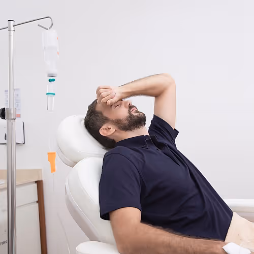 A person relaxing in a comfortable chair during an IV therapy session for rapid rehydration after alcohol consumption.