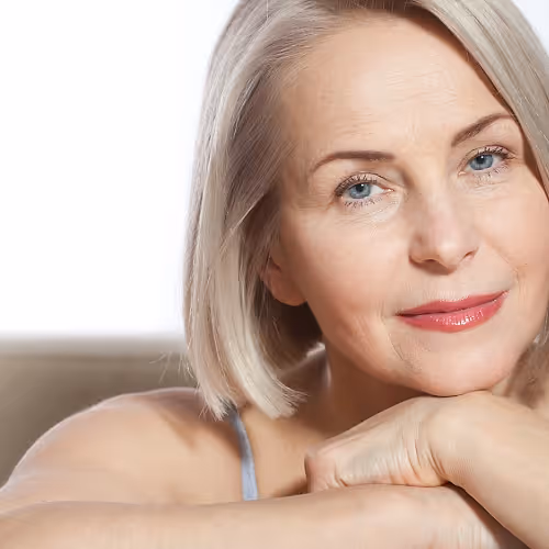 A woman in her 50s receives IV therapy to support menopausal symptom relief, looking calm and comfortable in a wellness setting.