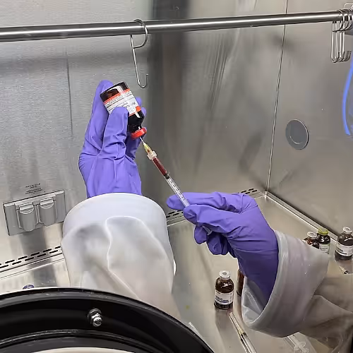 Licensed professional preparing an IV infusion in a clinical setting.